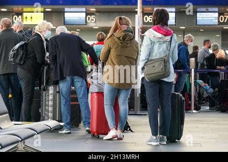 Schkeuditz, Deutschland. Oktober 2021. Reisende warten mit ihrem Gepäck beim Check-in am Flughafen Leipzig/Halle. Das erste Wochenende der Herbstferien in Sachsen ist eine geschäftige Zeit am Flughafen. Insgesamt starten am Samstag und Sonntag 50 Flugzeuge von den Flughäfen Leipzig/Halle und Dresden in Sachsen zu Urlaubszielen wie Spanien, der Türkei, Griechenland und Italien. Kredit: Peter Endig/dpa-Zentralbild/dpa/Alamy Live Nachrichten Stockfoto