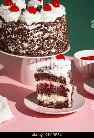 Schwarzwalder Kirschtorte, schwarzer Waldkuchen, raues Licht, Tischhintergrund im Sonnenlicht, modernes Stillleben, Kirschdessert auf modernem Hintergrund Stockfoto