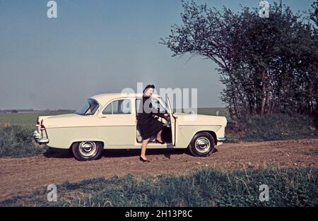 Ein Vintage-Farbfoto aus dem Jahr 1959, das eine Frau zeigt, die bei einem Ford Zodiac steht. Sie hat einen Fuß in die Fahrerseite des Autos. Aufgenommen in Suffolk England. Stockfoto