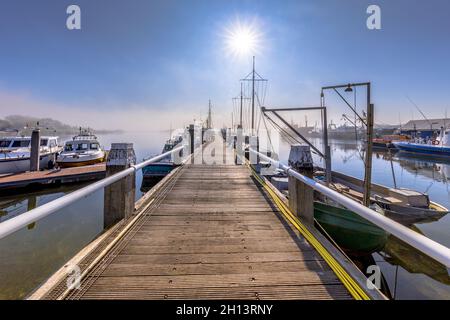 Verschiedene Schiffe vertäuten an einem Holzkai im Hafen in der Haringvliet-Bucht, Provinz Zeeland, Niederlande. Stockfoto