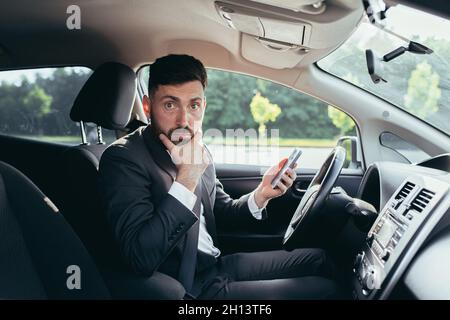 Der Mann, der im Auto saß, war überrascht, die Nachrichten vom Telefon zu lesen Stockfoto