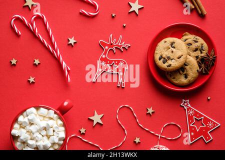 Weihnachtsplätzchen, heiße Schokolade mit Marschmalchen, festliche Dekorationen auf rotem Hintergrund. Flach liegend, Draufsicht. Stockfoto