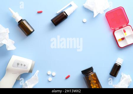 Grippebehandlungen. Nasensprays, Pillen zur Behandlung von Erkältungen, Taschentücher, Digitalthermometer auf pastellblauem Hintergrund. Flach liegend, Draufsicht, Kopierbereich. Stockfoto