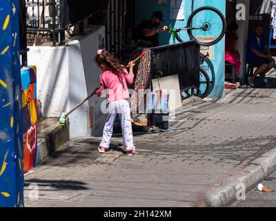 Medellin, Antioquia, Kolumbien - Dezember 23 2020: Kleines Mädchen fegen den Eingang ihres Hauses Stockfoto