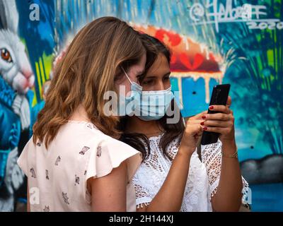 Medellin, Antioquia, Kolumbien - Januar 6 2021: Kaukasische und lateinische Freunde suchen das Telefon gegen städtischen Hintergrund Stockfoto