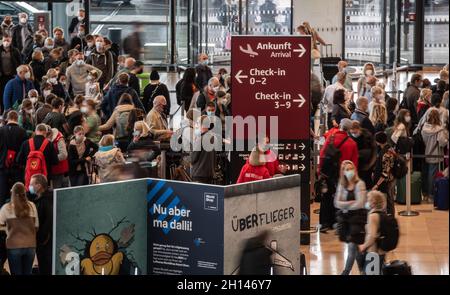 Berlin, Deutschland. Oktober 2021. 16. Oktober 2021, Schönefeld: Reisende stehen dicht beieinander vor einem Check-in-Schalter am Flughafen BER. Foto: Paul Zinken/dpa Kredit: dpa picture Alliance/Alamy Live News Stockfoto