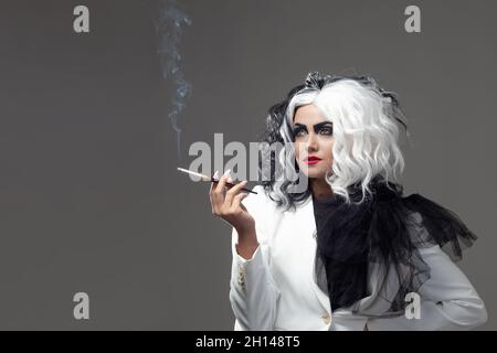 Eine tödliche Schönheit in einem gewagten Modebild mit schwarzen und weißen Haaren. Ein rebellisches stylisches Bild für Halloween. Eine junge Frau in einem schwarz-weißen Outfi Stockfoto