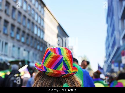 Düsseldorf, Deutschland. Oktober 2021. Ein Teilnehmer der Christopher Street Rallye geht mit einem Regenbogenhut durch das Stadtzentrum. Dieses Jahr steht das Motto „Solidarität hat viele Farben“. Die Aktionen des Christopher Street Day (CSD) erinnern an eine Reihe gewaltsamer Konflikte zwischen Homosexuellen und Polizisten in der Christopher Street in New York im Jahr 1969. Quelle: Oliver Berg/dpa/Alamy Live News Stockfoto