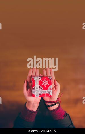 Hände mit weihnachtsgeschenk in rotem Papier mit Bereich für Text, vertikal gewickelt Stockfoto