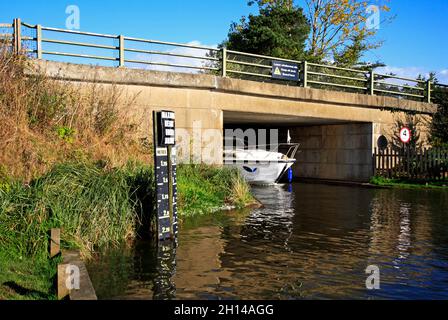 Ein Kreuzer auf dem Fluss Ant auf den Norfolk Broads, der unter der Straßenbrücke A1062 in Ludham, Norfolk, England, Großbritannien, vorbeifährt. Stockfoto