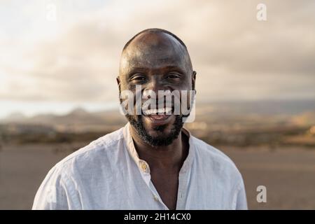 Glücklicher afrikanischer Mann, der während der Sommerferien in der Kamera am Strand lächelt Stockfoto