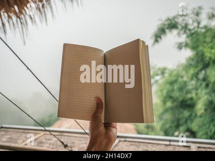 Die Hand des Weibchens hält eine leere Buchseite in der Natur Stockfoto