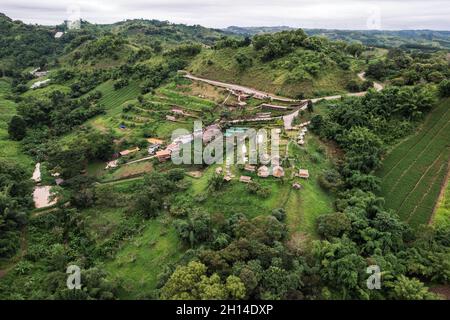 Luftaufnahme des Hüttenresort am Hang zwischen den Bergen im tropischen Regenwald an regnerischen Tagen in Thailand Stockfoto