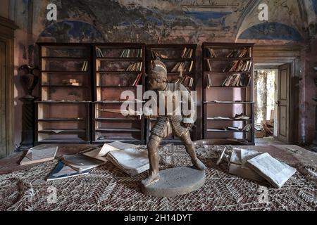 Alte Bronzestatuette auf einem alten Tisch im Wohnzimmer, in einem verlassenen Haus. Urbex in Italien. Stockfoto