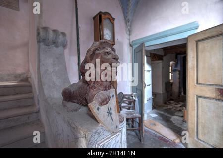 Der Eingang ist mit Fresken geschmückt und mit Gemälden und Statuen ausgestattet, die Löwen aus einem verlassenen Haus in Norditalien darstellen. Urbex in Italien Stockfoto