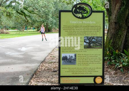 NEW ORLEANS, LA, USA - 19. SEPTEMBER 2021: Eichenholzschild im Audubon Park mit verschwommenem Rollschuhläufer im Hintergrund Stockfoto