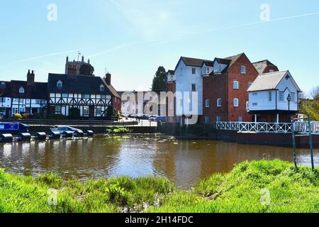 Diese hübsche Aussicht auf die alten Hütten am Fluss und die Tewkesbury Wassermühle am Fluss Avon bietet einen Blick auf die Abtei im Hintergrund. Stockfoto