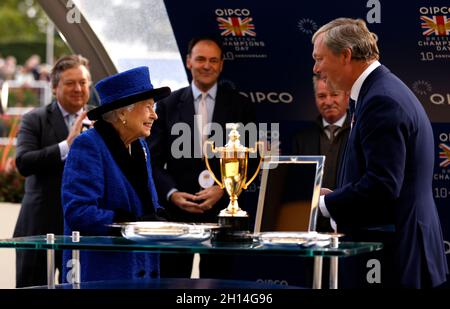 Queen Elizabeth II (links) überreicht die Trophäe dem Trainer William haggas nach dem Queen Elizabeth II Stakes (gesponsert von Qipco)-Rennen während des Qipco British Champions Day auf der Ascot Racecourse. Bilddatum: Samstag, 16. Oktober 2021. Stockfoto