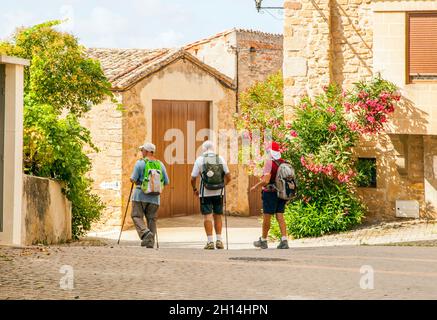 Pilger, die durch das Dorf Villamayor de Monjardin wandern, während sie den Jakobsweg in der Landschaft Navarras, Spanien, durchqueren Stockfoto