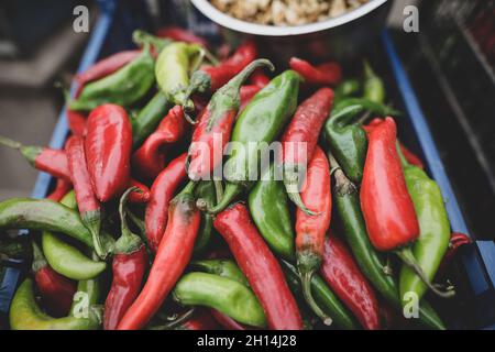 Bild mit geringer Schärfentiefe (selektiver Fokus) mit scharfem roten und grünen Paprika, die von einem rumänischen Mann aus seinem Garten in einem ländlichen Gebiet verkauft wurde. Stockfoto