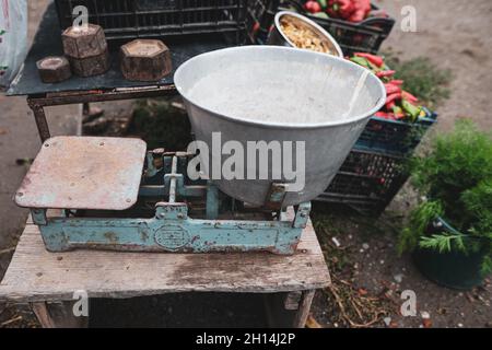 Geringe Schärfentiefe (selektiver Fokus) mit alten Skalengewichten auf dem Tisch eines rumänischen Bauern, der Gemüse aus seinem Garten in einem ländlichen Raum verkauft Stockfoto