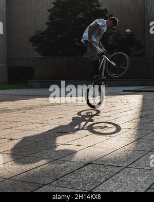 Silhouette eines jungen Mannes auf BMX-Rad gegen den Sonnenuntergang. BMX-Fahrer macht Tricks in der Luft auf einem Fahrrad. BMX-Freestyle. Gesundes Lifestyle-Konzept. Stockfoto