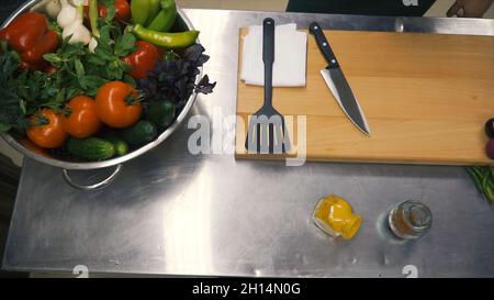 Frisches Rohes Frühlingsgemüse. Clip. Essen Vegetarisch Hintergrund. Tomaten, Gurke, Radieschen, Salatblätter im Metallkorb. Draufsicht Stockfoto