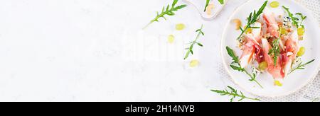 Vorspeise mit Birne, Blauschimmelkäse und Schinken für den Urlaub auf einem weißen Teller. Draufsicht, Banner, flaches Lay Stockfoto