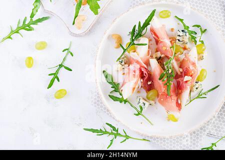 Vorspeise mit Birne, Blauschimmelkäse und Schinken für den Urlaub auf einem weißen Teller. Draufsicht, flach liegend Stockfoto