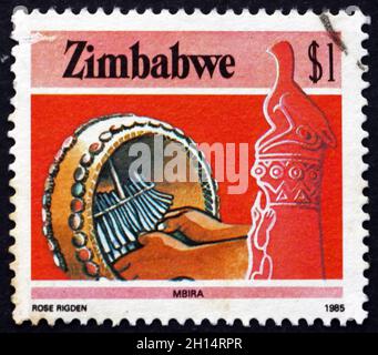 SIMBABWE - UM 1985: Eine in Simbabwe gedruckte Marke zeigt Zimbabwe Vogel und Mbira Trommel, Musikinstrument, um 1985 Stockfoto