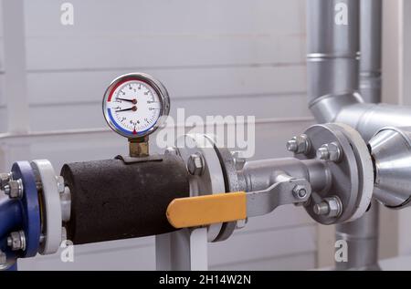 Manometer und Thermometer zur Messung der Temperatur und des Drucks von Wasser in der Rohrleitung in einem Gaskesselraum. Stockfoto