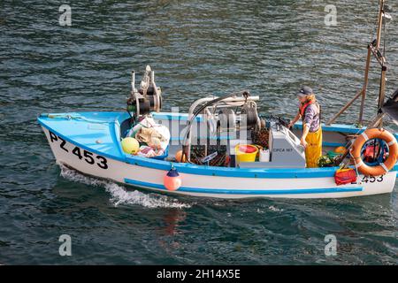 Mullion Cove, Cornwall, 16. Oktober 2021, die Menschen genossen die herrliche Herbstsonne bei Flut in Mullion Cove, Cornwall. Einige schwammen im Hafen, als ein Fischerboot mit seinem Fang von Krabben und Hummer zurückkehrte, während andere an der Hafenmauer fischten.das wärmere Wetter wird voraussichtlich das ganze Wochenende über dauern, mit heftigen Regenvorhersagen für die nächste Woche.Quelle: Keith Larby/Alamy Live News Stockfoto