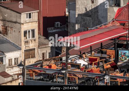 ISTANBUL, TÜRKEI - 12. OKTOBER 2021: Tischaufstellung auf dem Dach des Restaurants mit Blick auf das alte Gebäude. Straßencafé auf dem Dach des Gebäudes in Istanbul Stockfoto