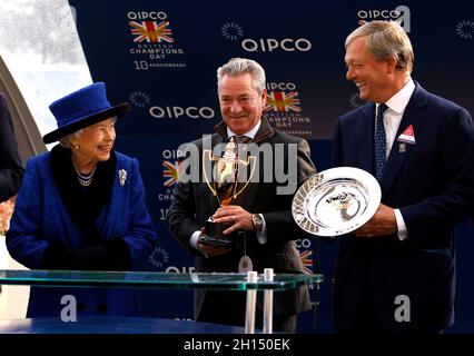 Queen Elizabeth II (links) überreicht die Trophäe dem Trainer William haggas (rechts) nach dem Queen Elizabeth II Stakes (gesponsert von Qipco)-Rennen während des Qipco British Champions Day auf der Ascot Racecourse. Bilddatum: Samstag, 16. Oktober 2021. Stockfoto