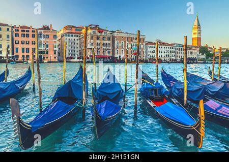 Aquarell-Zeichnung von Gondeln, die im Wasser des Canale Grande in Venedig festgemacht sind. Farbenfrohe Gebäude im Barockstil entlang des Canal Grande und des Glockenturms C. Stockfoto