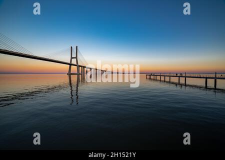 Faszinierender Blick auf die Vasco da Gama Brücke bei einem malerischen Sonnenuntergang in Sacavem, Portugal Stockfoto