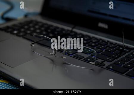 Nahaufnahme einer Brille auf dem Schreibtisch mit Laptop am Arbeitsplatz. Augenschutz Stockfoto