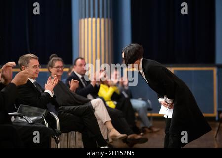 Kassel, Deutschland. Oktober 2021. Herta Müller, Literaturnobelpreisträgerin, verneigt sich nach der Verleihung des Jacob-Grimm-Preises für die deutsche Sprache bei der 20. Verleihung des Kulturpreises Deutsche Sprache. Neben ihr applaudiert ihr Mann, der Schriftsteller Harry Merkle (l.). Der Preis wird von der Eberhard-Schöck-Stiftung und dem Deutschen Sprachbund gefördert. Quelle: Sebastian Gollnow/dpa/Alamy Live News Stockfoto