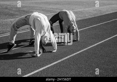 Flexible Mädchen Turnerinnen stehen in Krabbenposition auf der Leichtathletik-Strecke, Flexibilität Stockfoto