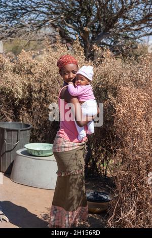 Alleinerziehende junge afrikanische Mutter in einem Dorf in Botswana, das Drama alleinerziehender Mütter aus der dritten Welt Stockfoto