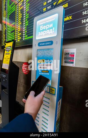 Moskau, Russland – 20. Februar. 20201. Hand mit einem Telefon auf dem Hintergrund des Ladegerätes mit Powerbank bei Kasansky Terminus Stockfoto