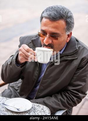 Porträt eines iranischen arabischen Geschäftsmanns, der in einem Einkaufszentrum Cappuccino trinkt Stockfoto