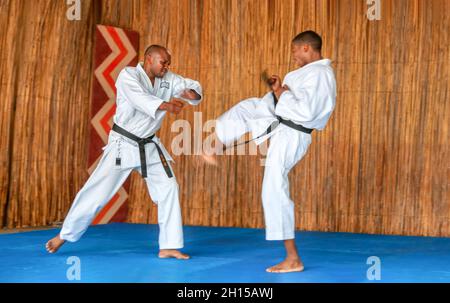 Afrikanische Männer, die Kumit an einem Dojo auf einem blauen Boden aufführen Stockfoto