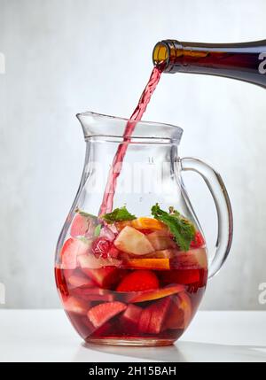 Rotwein Gießen in Krug von geschnittenen Früchten. Prozess der Herstellung von roten Sangria Stockfoto