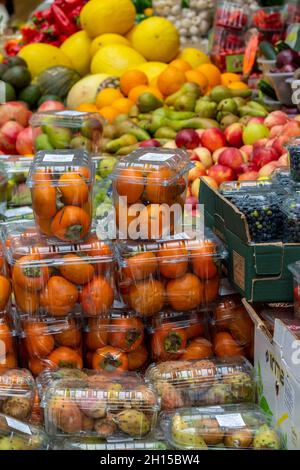 Eine Auswahl an frischem Obst, darunter Orangen, Äpfel und Zitronen, wird vor einem Obst- und Gemüsestandplatz auf einem Marktplatz in der Stadt ausgestellt. Stockfoto