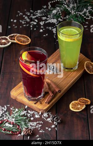 Stillleben Komposition mit zwei Gläsern roten und grünen erfrischenden Wintergetränk oder Glühwein mit Orange in Scheiben geschnitten auf einem dunklen Holzhintergrund mit sn Stockfoto