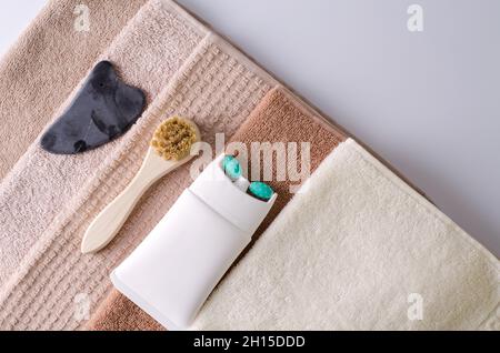 Lifting-Creme in einem Rohr mit einer Massage-Walzendüse, Bürste aus Naturborsten und Gouache aus Naturstein für einen Stapel Handtücher, Zubehör Stockfoto