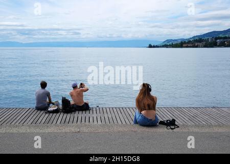 Montreux, Schweiz - 3. Juli 2021. Touristen entspannen sich am Ufer des Genfer Sees direkt neben der Statue von Freddie Mercury in Montreux, Schweiz Stockfoto