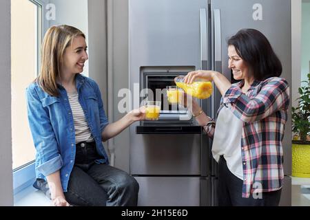Zwei Freundinnen mittleren Alters trinken Orangensaft in der Küche Stockfoto