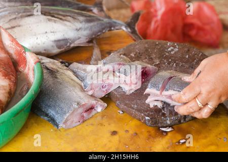 Schneiden Sie Thunfisch auf den Tisch eines Fischverkäufers auf dem Fischmarkt. Roher Thunfisch.der Verkäufer zerschnitt Thunfisch in Stücke. Stockfoto
